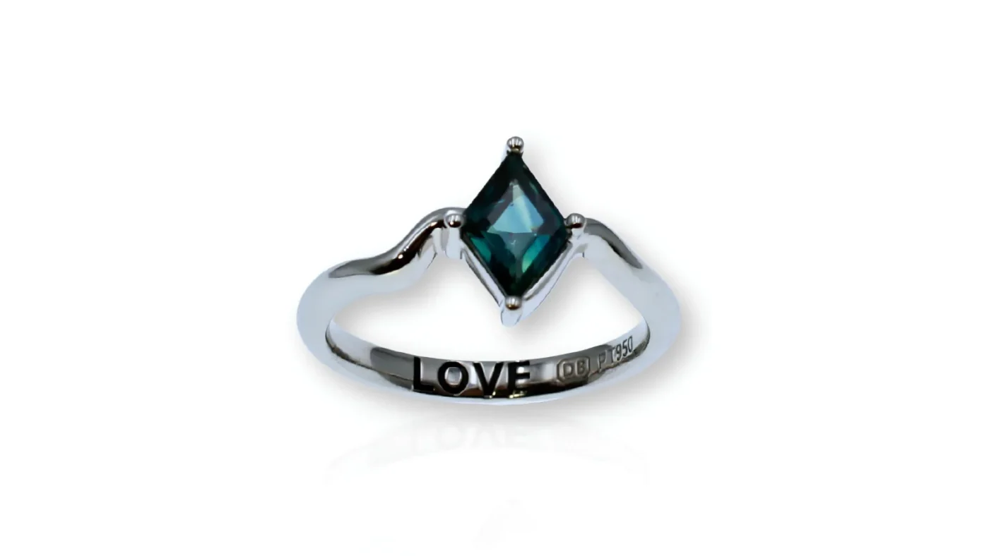 Custom platinum LOVE ring featuring a natural diamond shaped parti sapphire and hidden LOVE inscription
